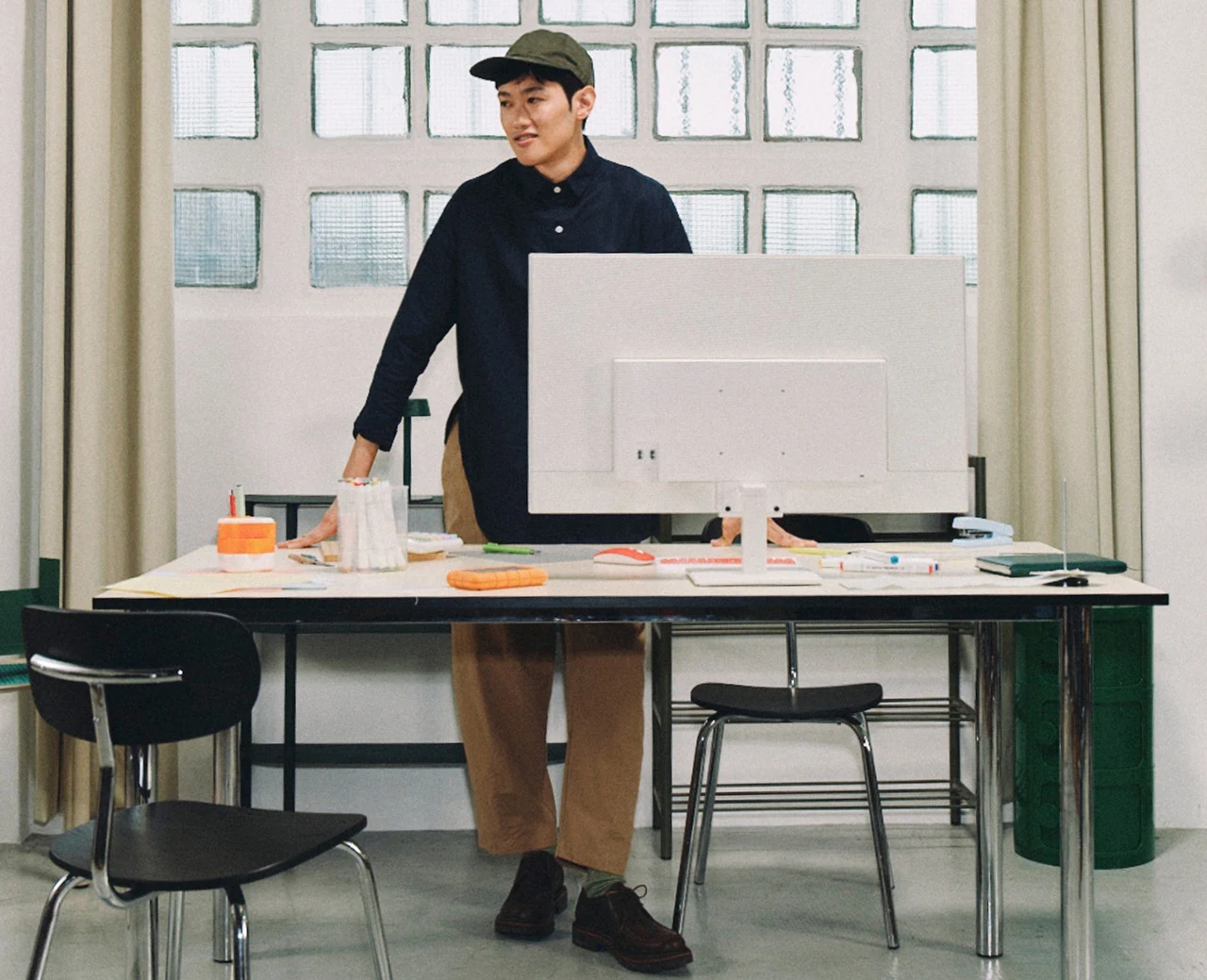 Person standing behind a desktop computer in a bright creative studio.
